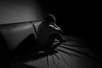 Man with depression sitting in a dark room.  Depression is a low mood that lasts for a long time,...