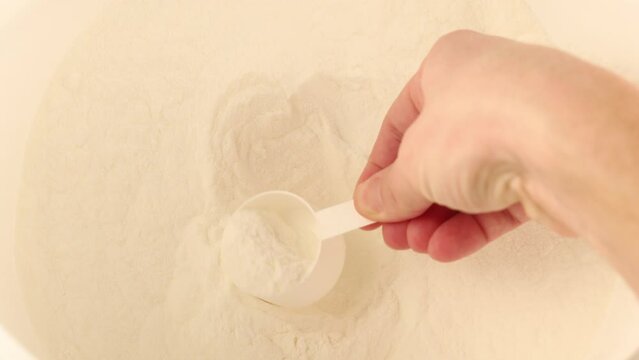 The hand scoops the gainer into the jar