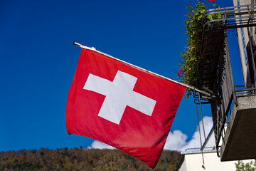 Swiss flag waving at balcony at Swiss City of Biel Bienne, Canton Bern, on a sunny autumn day. Photo taken November 10th, 2022, Biel Bienne, Switzerland. - obrazy, fototapety, plakaty