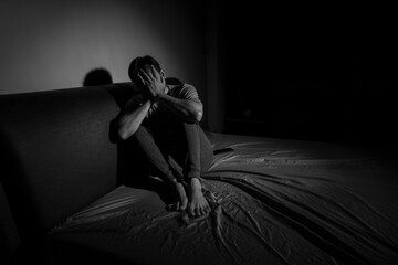 Man with depression sitting in a dark room.  Depression is a low mood that lasts for a long time,...