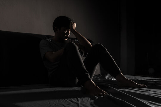 Man with depression sitting in a dark room.  Depression is a low mood that lasts for a long time, and affects your everyday life.