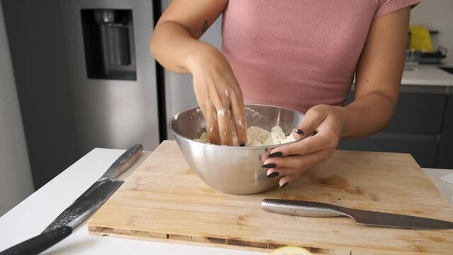 Young unrecognizable Venezuelan woman mixing arepa dough at kitchen.