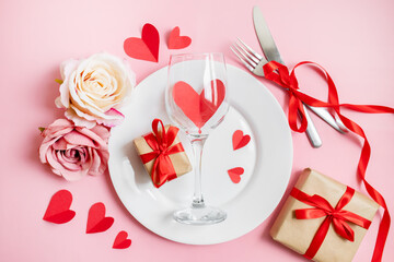 classic festive table setting in valentine's day style with gifts and hearts on a pink background. copy space. top view. 14 february concept