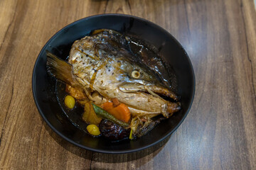 Japanese food concept. Salmon head steamed with sweet sauce and vegetable in Japanese style. Salmon kabutoni steamed, Japanese food style. Salmon head boiled in soy sauce with vegetables. 