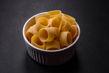 Raw uncooked pasta in a white ceramic bowl with spices and herbs