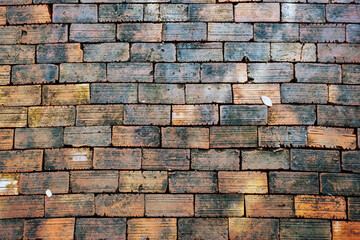 Top view of old bricks paving stones footpath pattern on sidewalk outdoors as brickwork weave texture or abstract stone paver background. Top view of pavement surface. Bricks Background and texture.