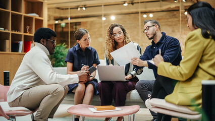 Multi Ethnic Group of People Working on Developing Growth Ideas Based on Data. Energetic Teammates in a Meeting Room in an Office, Analyzing Charts Using Tablet and Laptop. Wide Shot