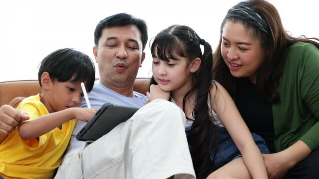 Asian father and mother looking children drawing a picture on teblet computer at home.