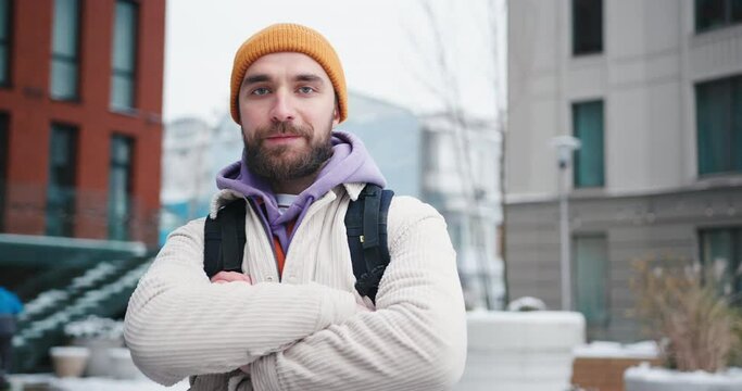 Portrait of adult handsome arab hipster man with beard wearing yellow hat walkng outdoors in the city streets at winter