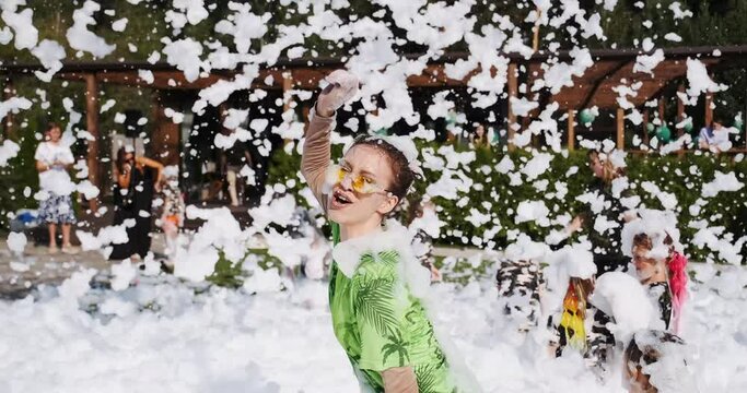 Happy emotion woman dance on foam party, enjoy music. Female animator on children holiday have fun with bubble soap foam. Kids playing with lather, soapsuds