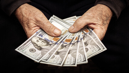 Grandfather holds money in his hands. An elderly man counts dollars