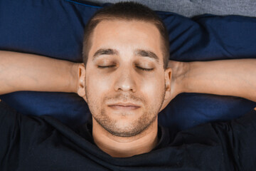 Top view of a handsome young man sleeping comfortably on the bed in his bedroom at night. Bachelor...