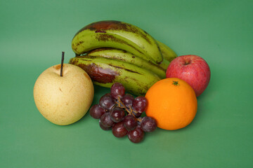 Pear, grape, banana, orange and apple fruits isolated on green background