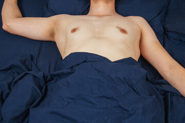 Handsome young man sleeping comfortably on the bed at night in his bedroom without clothes....