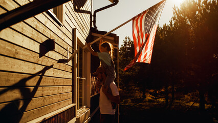 Proud Patriotic Dad Holding His Young Daughter of His Shoulders, Helping Her to Put the United...