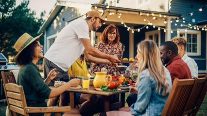 Handsome Man Cooking Grilled Corn and Other Vegetables. Bringing Food to a Big Outdoors Table with Family Members and Friends. Diverse Group of Adults and Children Having a Vegetarian Dinner.