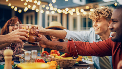 Close Up of a Family and Multiethnic Diverse Friends Gathering Together at a Garden Table Dinner. Old and Young People Raising and Toasting Glasses with Fresh Orange Juice and Celebrating an Event.
