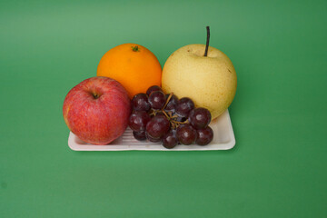 Pear, grape, banana, orange and apple fruits isolated on green background