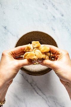 Home baked garlic cloves being squished in to a bowl