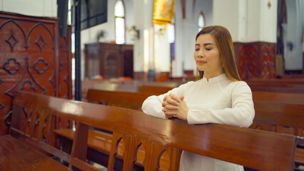 Asian Vietnamese woman praying in empty christian church with cross, architecture design. Religious beliefs. Catholic religion. Jesus worship. People lifestyle.