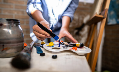 Fototapeta premium Young artist prepares colours to paint in dark creative studio.