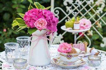 romantische Dekoration mit Blumenstrauß in Pink, vintage Kaffeetasse und Windlichtern	
