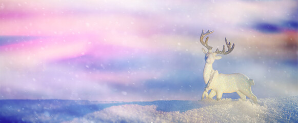 Christmas winter background, banner - view of an ice deer on a snowdrift in a winter forest with colorful background and copy space for text