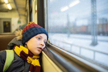 a boy sits in a suburban train by the window alone in winter