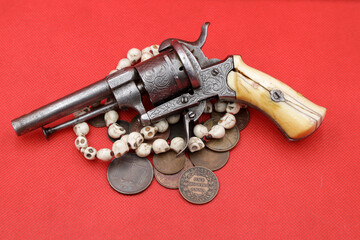 Vintage revolver and old coins of India on red background