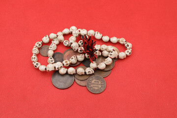 Old coins of India and rosary on red background