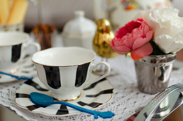 Black and white stripes porcelain tea sets, including teacups, plates, spoons and sugar bowl on a silver tray covered with lace, decorated with tulips, a golden bird and cinnamon