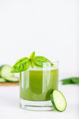 Cold cucumber lemonade with basil and lemon in a glass on table.