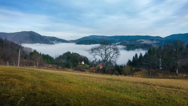 The fog is moving in the mountain valley above the lake. Cloudy morning in the mountains. Timelapse with a view of the village houses, lake and mountains. Tara, Serbia. High quality 4k footage