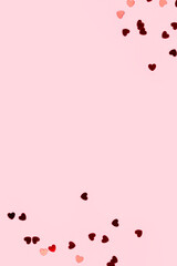Red confetti in a heart shape on a pink background. Concept with place for text.