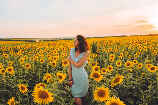 Happy young woman in blue dress in a sunflower field