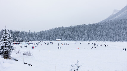 Fototapeta premium Lake Louise Ice Skaters, Ice Skating on Frozen Lake in Mountains