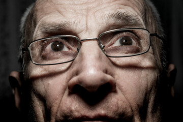 Head photo shot of old man with wrinkled face wearing eyeglasses.