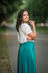 Portrait of a young beautiful dark-haired girl in a summer city park.