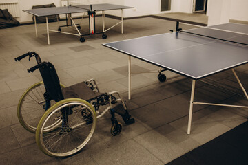 An adult disabled man in a wheelchair plays table tennis. A game of ping pong.