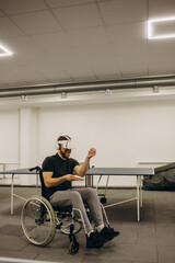 A young athlete in a wheelchair plays table tennis with the help of virtual reality glasses.