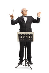 Full length portrait of a music conductor standing in front of a sheet music stand and directing a...