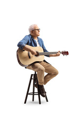 Mature musician sitting on a chair playing an acoustic guitar and looking to the side