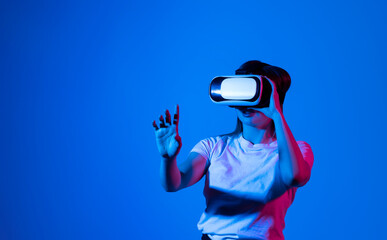 Woman in white shirt wearing VR glassess, VR set equipment for exploring a metaverse. Concept of metaverse, virtual reality, future, technology and internet.
