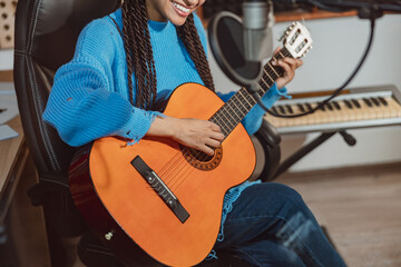 Cropped image of a pretty woman guitarist playing guitar and rehearsing new song in professional...