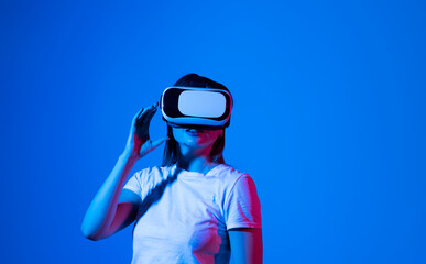 Brunette woman in white shirt wearing VR glassess, VR headset equipment for exploring a metaverse with a friends.