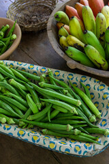 Bunches of banana and okra in rustic and decorated wooden bowls for sale after harvest in a popular economy farm. Sao Paulo state, Brazil