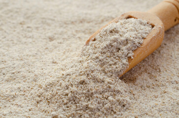 Rye flour background with wooden spoon, top view. Texture, background of peeled rye flour with a...