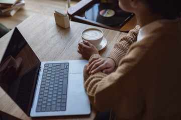 Overhead view of a woman drinking coffee and using laptop with empty blank screen at a cafe. Copy space - Powered by Adobe