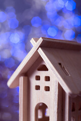 small decorative plywood house close-up against the background of blue bokeh lights