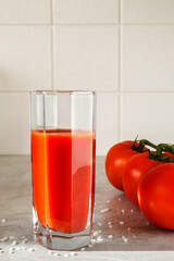 There is a glass of tomato juice and tomatoes on the table